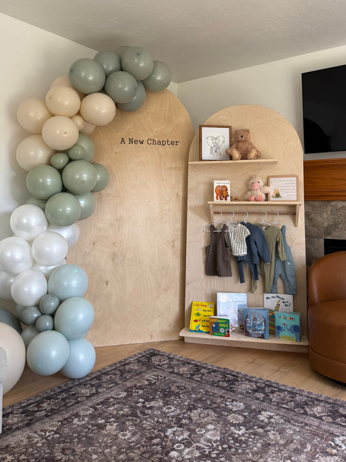 Balloon arch, shelves with toys, and a brown chair.