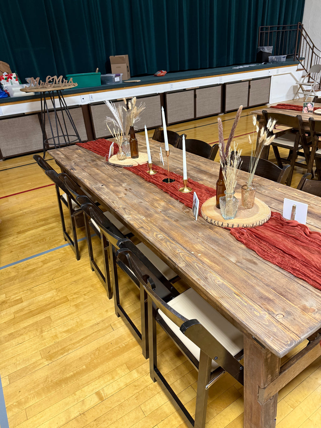 Long wooden table set with decorative items in a gymnasium setting