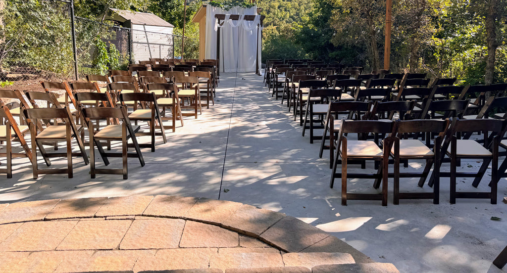 Outdoor wedding setup with rows of chairs on a concrete path.