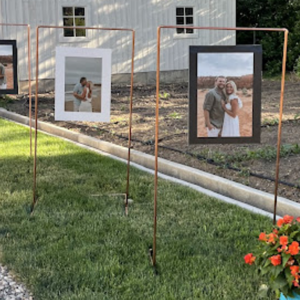 Metal photo stands with framed pictures in a garden setting