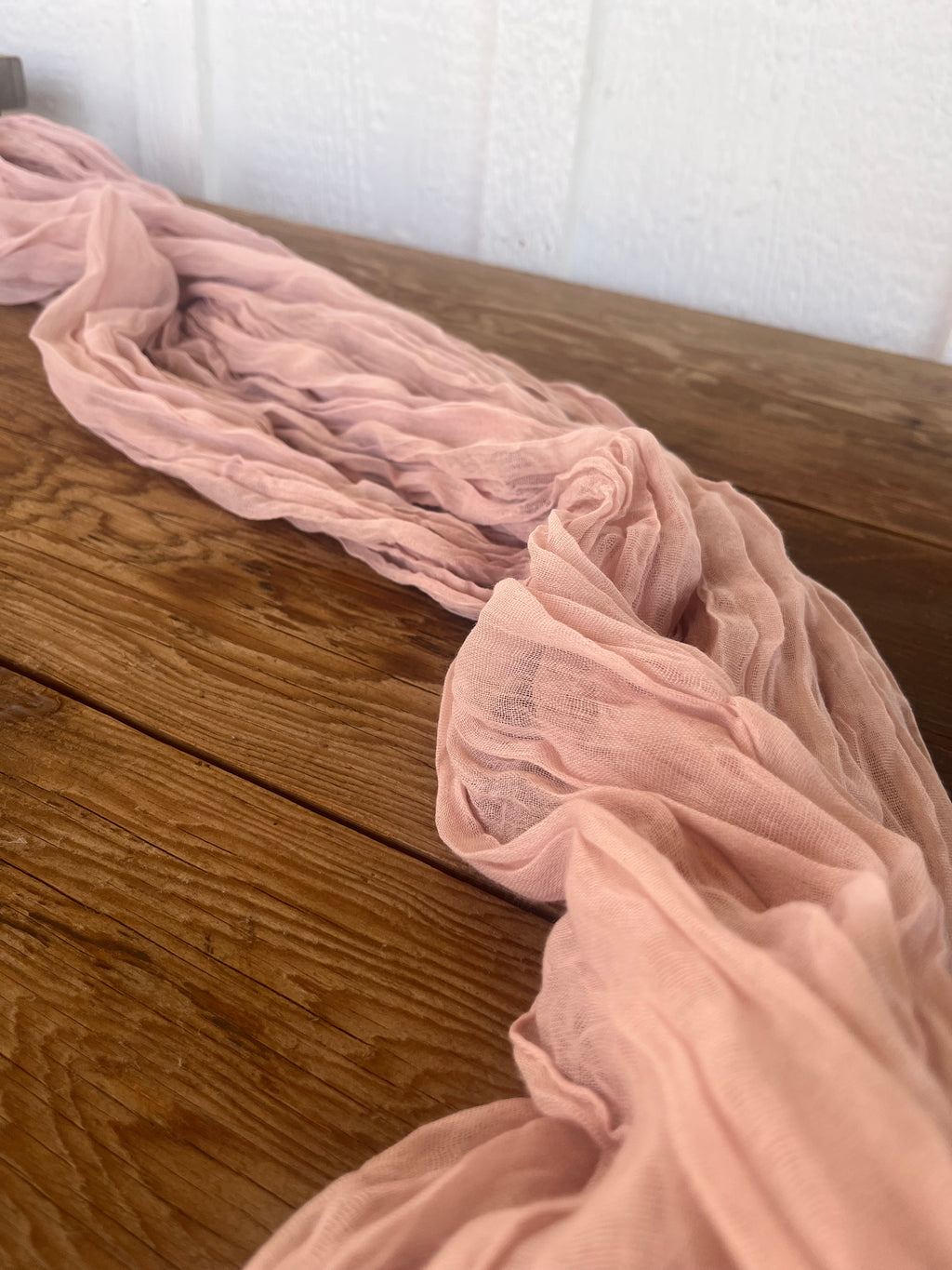 Pink scarf draped over a wooden surface 