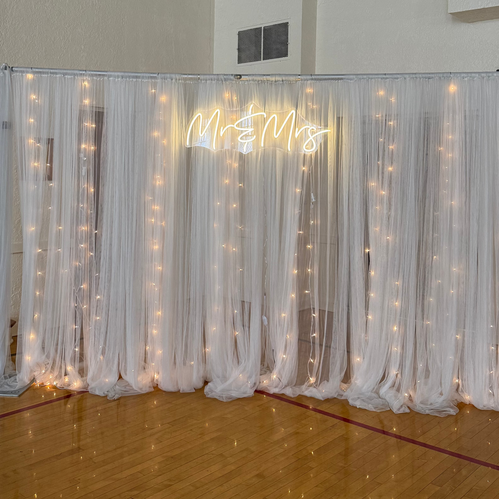 Decorative screen with fairy lights and text in a room with wooden floor and white walls.