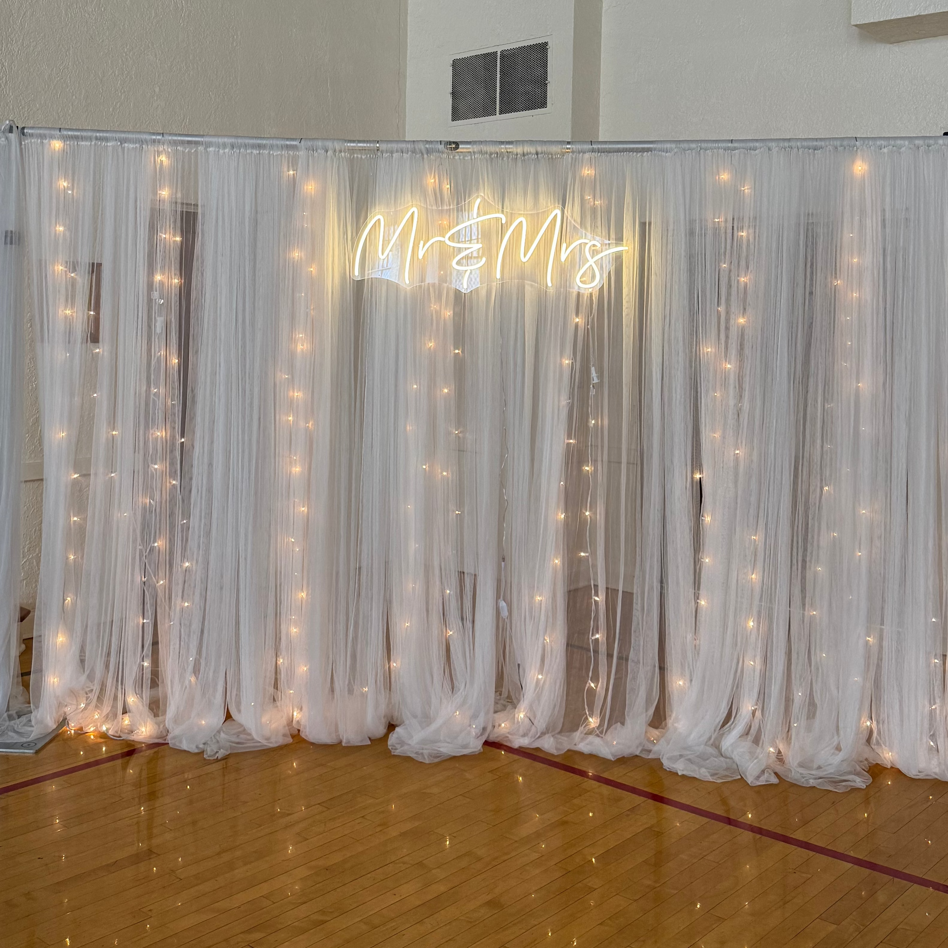 Decorative screen with fairy lights and text in a room with wooden floor and white walls.