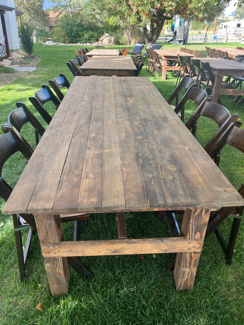 Wooden outdoor dining tables and chairs on a grassy area